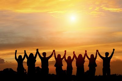 a group of people standing in front of a sunset